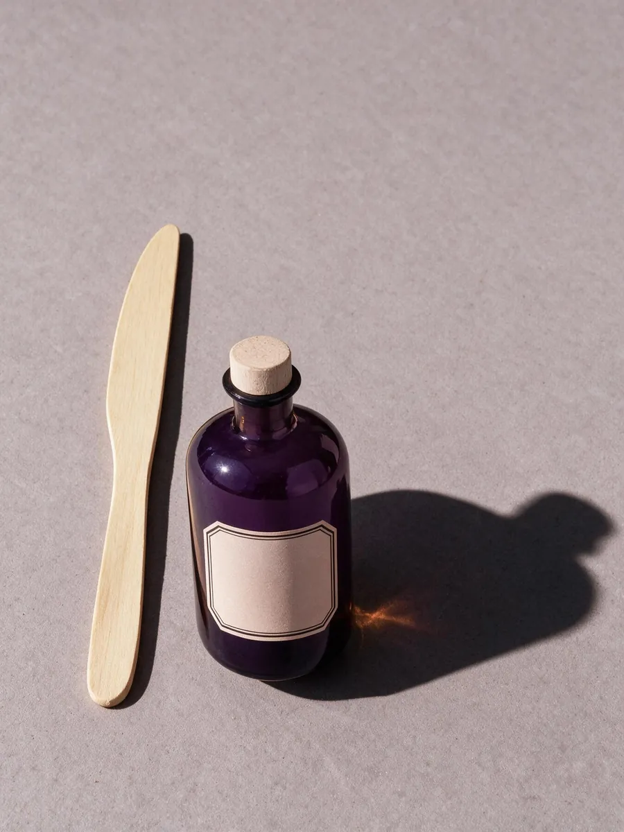 The apothecary bottle on a grey surface, with the glass turned from amber to purple