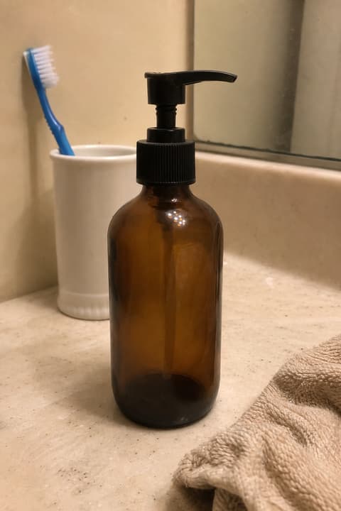 Seller's phone snap of an amber pump bottle on a bathroom counter