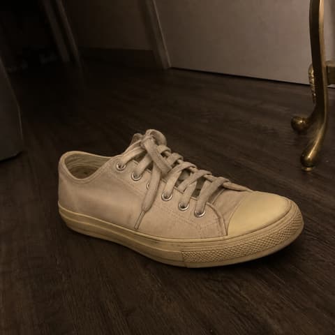 Dim phone snap of a canvas sneaker on an apartment floor