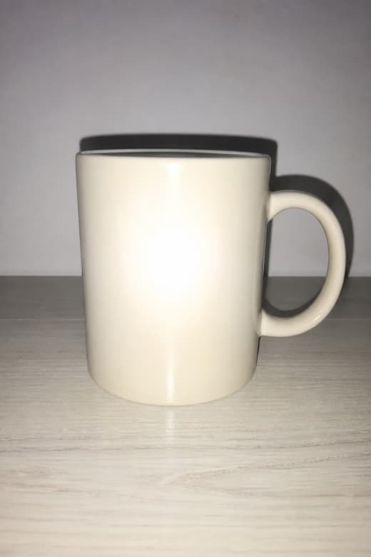 Phone photo of a cream ceramic mug ruined by direct flash