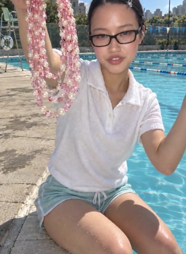 UGC video ad: a woman by a pool holds up a pink pearl necklace